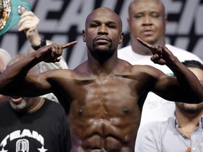 FILE - In this Sept. 12, 2014, file photo, Floyd Mayweather Jr. poses on the scale during a weigh in for a fight against Marcos Maidana in Las Vegas. Mayweather Jr. said Wednesday, June 14, 2017,  he will come out of retirement to face UFC star Conor McGregor in a boxing match on Aug. 26. Mayweather, who retired in September 2015 after winning all 49 of his pro fights, will face a mixed martial arts fighter who has never been in a scheduled 12-round fight at the MGM Grand arena. The fight will take place in a boxing ring and be governed by boxing rules.