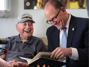 Ovil Lesperance, 102, looks over his 1930 Assumption high school  year book with Windsor Mayor Drew Dilkens on June 13, 2017. Dilkens is trying to visit as many centenarians as possible in conjunction with the city's 125 anniversary.