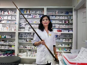 Sara Etemad-Rad, pharmacy manager/owner of the Neighborhood Drug Store, displays the pool cue she used recently to fight off a knife-wielding robber.