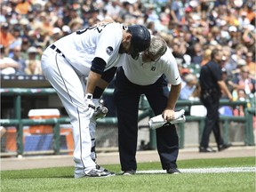 Detroit Tigers' J.D. Martinez talks with trainer Kevin Rand after fouling a pitch off his ankle in the seventh inning of a baseball game against the Kansas City Royals, June 29, 2017, in Detroit.