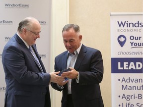 WindsorEssex Economic Development Corporation CEO Stephen MacKenzie, left, presents retiring WEEDC board chair Marty Komsa with a commemorative plaque during WEEDC's annual general meeting June 20, 2017, at the Fogolar Furlan Club.