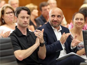 Tim Hampson, front left, and Pierre Tessier applaud after a speaker apposed the location of a new fire hall during the LaSalle Council meeting at Town Hall July 11, 2017.