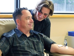 Spitfires vice-president of hockey operations Bill Bowler gives blood under the watchful eyes of Nick Bourque, cast member from Evil Dead: The Musical by Korda Artistic Productions on Wednesday at the Windsor Blood Donor Clinic.