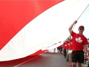Canada Day participants carry a massive maple leaf along Wyandotte Street East as part of Windsor's Canada Day Parade.