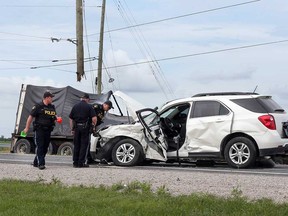 OPP investigators examine the compact SUV that was involved in the accident at Highway 77 and Lakeshore Road 310 on July 26, 2017. The wreckage of a transport truck is visible in the background.