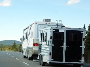 A motor home with trailer heads down the road.