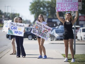Miss Tecumseh pageant contestants, from left, Kallie Szarka, 22, Chelsie Lefler, 22, Katja Bekcic, 17, and Kyara Busico, 18, try to attract drivers into the Miss Tecumseh Charity of Choice Car Wash, July 29, 2017.  The group of young women were raising money for the Sick Kids Foundation.