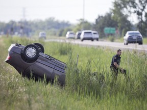 An OPP officer works at the scene of a single-vehicle rollover on Highway 3, west of Manning Road on Tuesday, July 25, 2017.