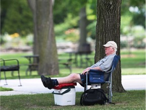 Ed Baillargeon kicks up his feet and relaxes under trees at the Coventry Gardens in Windsor, Monday.