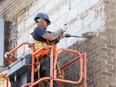 A worker with Jones Group chips away at the front facade at the  Government of Canada offices at 441-467 University Avenue West on Aug. 24, 2017.