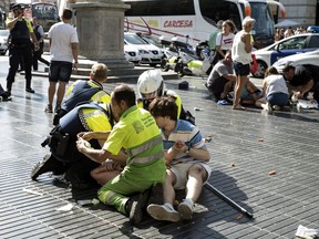 Medics and police tend to injured people near the scene of a terrorist attack in the Las Ramblas area on Aug. 17, 2017 in Barcelona, Spain. Officials say 13 people are confirmed dead and at least 100 injured after a van plowed into people in the Las Ramblas area of the city Thursday afternoon.