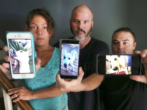 Lisa Delaney, left, Michael Delaney and their son, Nate Delaney, display photos of their late Jack Russell Terrier, Snoopy who perished in the flood at their home in Windsor, on Aug. 30, 2017.
