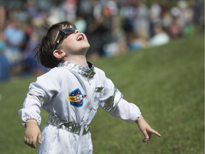 John Guthrie-Hurst, 5, dressed in an astronaut suit, looks up at the sun along Windsor's waterfront during a solar eclipse on Aug. 21, 2017.