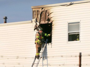 A firefighter checks out a second-story window after a fire at 1950 Continental Ave. in west Windsor on July 31, 2017.
