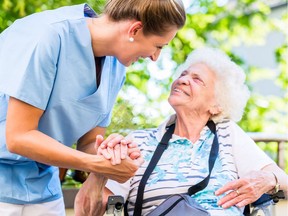 A caregiver holds a senior's hand.