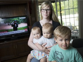 Kendra Holtby and her three children — nine-month-old twins Jessa left, and Adalynn, and Tanner, 3 — closely watch the news coming out of Houston, Texas, while visiting her parents home in Belle River on Monday. Holtby's husband, Tim, is in Calgary on business. The entire family is unable to return to Houston due to severe flooding.