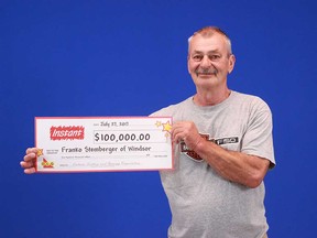 Windsor resident Franko Stemberger holds up the $100,000 prize cheque he won from playing a $5 scratch game.