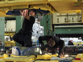 Saturn Tool & Die employees work on a stamping press in this 2013 file photo.
