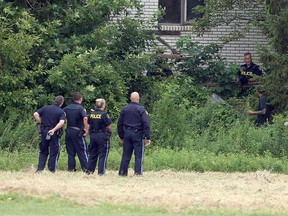 OPP officers stand with an unholstered Taser while they surround a man suspected of a break-in attempt in Tecumseh on the morning of Aug. 4, 2017.