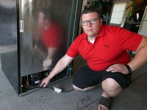 Tom Catherwood displays his Frigidaire kitchen appliance at his home in Amherstburg, Ontario.   Catherwood discovered a fire near the compressor of the Frigidaire refrigerator.  He is warning other Frigidaire owners to be aware of his situation.