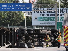 Windsor firefighters deal with a transport truck that rolled onto its side at the entrance to the Ambassador Bridge on Aug. 25, 2017.