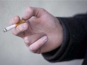 A smoker holds a cigarette during a smoke break outside a building in North Vancouver, B.C. Monday, Jan. 20, 2014.