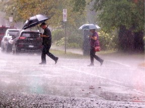 Pedestrians make their way through torrential rain in downtown Windsor on Aug. 29, 2017.