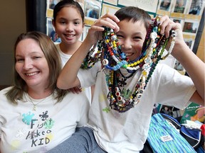 Former patient Dereck Lau, 13, has some fun with his heavy, Beads of Courage necklaces with his mother Rory, left, and sister Morgyn, 11, at Windsor Regional Hospital's Met Campus on Sept 12, 2017.