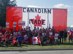 Striking employees from the CAMI assembly plant in Ingersoll stood in front of giant flag constructed by workers on Sept. 20, 2017.