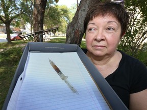 Peg Dorner keeps her distance from a dirty hypodermic needle  she found Saturday morning while dethatching her lawn.