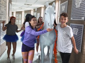 Massey international students Karlie Stam Yidanchang, 17,  front left, and Albert Qlyi, 14, parade through the hallways with school mascot Morris the Mustang during orientation on Aug. 30, 2017.