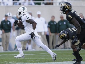 Running back LJ Scott of the Michigan State Spartans breaks down field while being pursued by defensive backs Davontae Ginwright and Stefan Claiborne of the Western Michigan Broncos during the second half at Spartan Stadium on Sept. 9, 2017 in East Lansing, Mich.