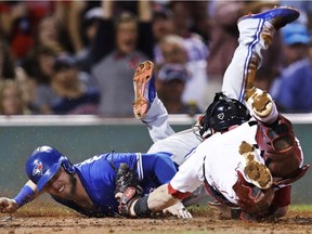 Toronto's Josh Donaldson, left, scores on a Kendrys Morales single as the ball gets away from Boston's catcher Christian Vazquez during the third inning of a baseball game at Fenway Park in Boston on Sept. 27, 2017.