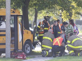 Windsor firefighters tend to children after the school bus they were riding on struck a tree at the intersection of Brock and Well streets on Wednesday.