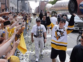 In this June 14, 2017, photo, Pittsburgh Penguins captain Sidney Crosby hoists the Stanley Cup for fans during a parade in Pittsburgh.