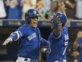 Toronto Blue Jays' Ryan Goins, left, celebrates his grand-slam against the New York Yankees with Richard Urena in the sixth inning in their American League MLB baseball game in Toronto on Friday, September 22, 2017. THE CANADIAN PRESS/Fred Thornhill