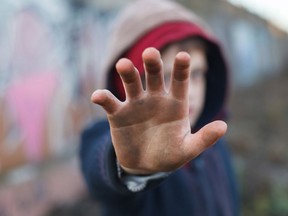 Dramatic portrait of a homeless boy, dirty hand, poverty, city, street.