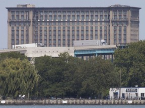 Transport trucks cross the Ambassador Bridge on Sept. 12, 2017, while the Michigan Central Station stands in the background. Both are owned by Matty Moroun.