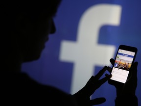 A woman checks the Facebook Inc. site on her smartphone whilst standing against an illuminated wall bearing the Facebook Inc. logo in this arranged photograph in London, U.K., on Wednesday, Dec. 23, 2015. Facebook Inc.s WhatsApp messaging service, with more than 100 million local users, is the most-used app in Brazil, according to an Ibope poll published on Dec. 15. Photographer: Chris Ratcliffe/Bloomberg

0128 biz wire facebook