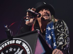 Kid Rock gives a speech behind a "United States of 'Merica" podium during his performance at Little Caesars Arena in Detroit on Sept. 12, 2017. His appearance was met by dozens of protesters from a civil rights group.
