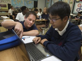 John Chittaro, geography teacher at Holy Names Catholic High School, left, helps Minjun Kim, 14, as he uses Google Earth for an in-class exercise on Sept. 21, 2017.