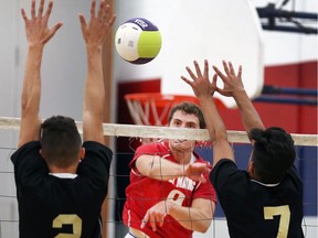 Jordan Gilham, centre, of Holy Names sends a ball between the blocks of Steven Shani, left, and Mihir Modi of Riverside during their senior boys volleyball game on Sept. 26, 2017, in Windsor.