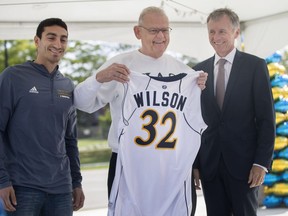 Mike Rocca, a 5th-year guard for the Lancers basketball team, presents David A. Wilson, centre, with a jersey along with Dr. Alan Wildeman, University of Windsor president,  during the inauguration of the David A. Wilson Commons, on Sept. 29, 2017. 
Dax Melmer, Windsor Star