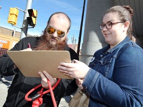 Volunteer Danielle Barron, right, holds the clipboard as Joshua Forbis signs a petition during the annual Chew on This! campaign in downtown Windsor to mark the International Day for the Eradication of Poverty Oct. 17, 2017.