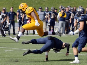 Queen's Gaels running back Marquis Richards hurdles an attempted tackle of Windsor Lancers Matt Gayer, below, and Daniel Metcalfe, right, in OUA first quarter football action at University of Windsor's Alumni Field on Saturday.