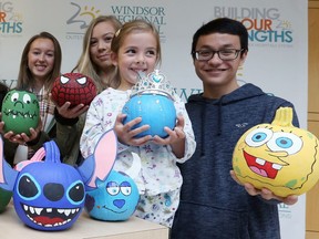 Five-year-old Evelyn Scott, second from right, holds her favourite pumpkin with Sandwich Secondary School students Gemma Fontanin, left, Naomi Laitinen and Matthew Lee during Pumpkins for Paediatrics event at Windsor Regional Hospital's Met Campus Monday Oct. 30, 2017.