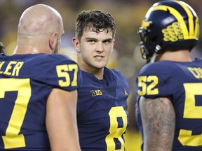 John O'Korn, middle, of the Michigan Wolverines talks with his teammates prior to the start of the game against the Michigan State Spartans at Michigan Stadium on Oct. 7, 2017 in Ann Arbor, Mich.