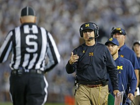 Coach Jim Harbaugh of the Michigan Wolverines talks with a referee in the first half against the Penn State Nittany Lions on October 21, 2017 at Beaver Stadium in State College, Pennsylvania.