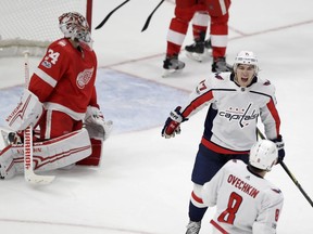 Detroit Red Wings goalie Petr Mrazek watches as Washington Capitals right wing T.J. Oshie (77) skates to congratulate left wing Alex Ovechkin (8) after Ovechkin's goal in overtime during an NHL hockey game, Oct. 20, 2017, in Detroit.