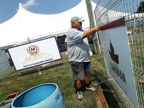 Al Baillargeon hangs signs as crews set up for the Tecumseh Cornfest on Aug. 21, 2013.